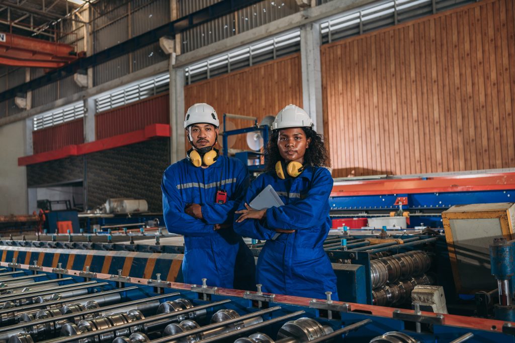 Portrait of industrial worker inspecting and check up machine at factory machines. Technician working in metal sheet at industry. Foreman checking Material or Machine.